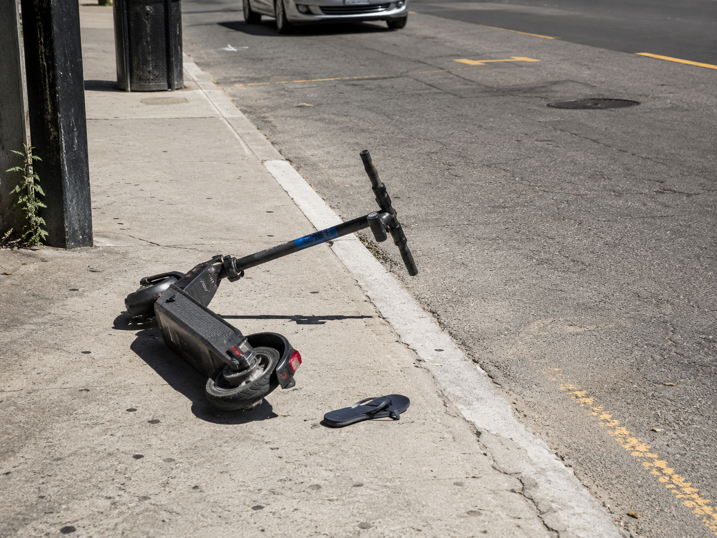 Trottinette électrique abandonnée avec une tong sur l'asphalte